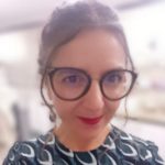 Woman in glasses and blurred background smiling to the camera